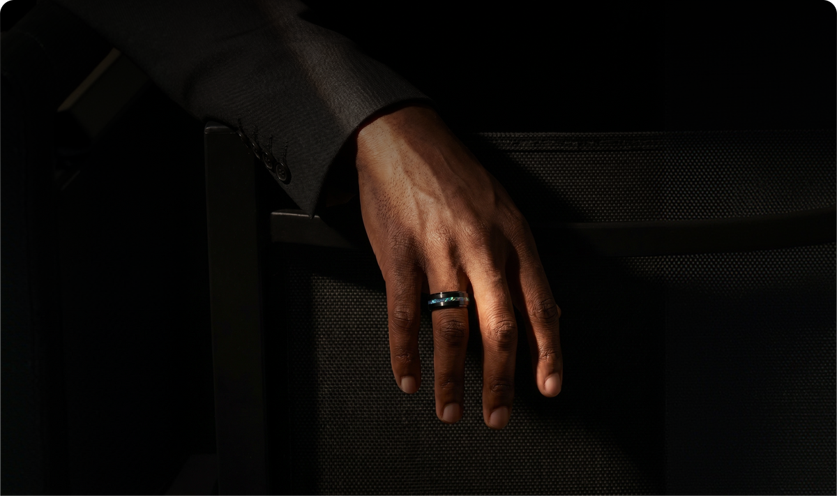 Man wearing a premium ring while seated in a dark tailored suit