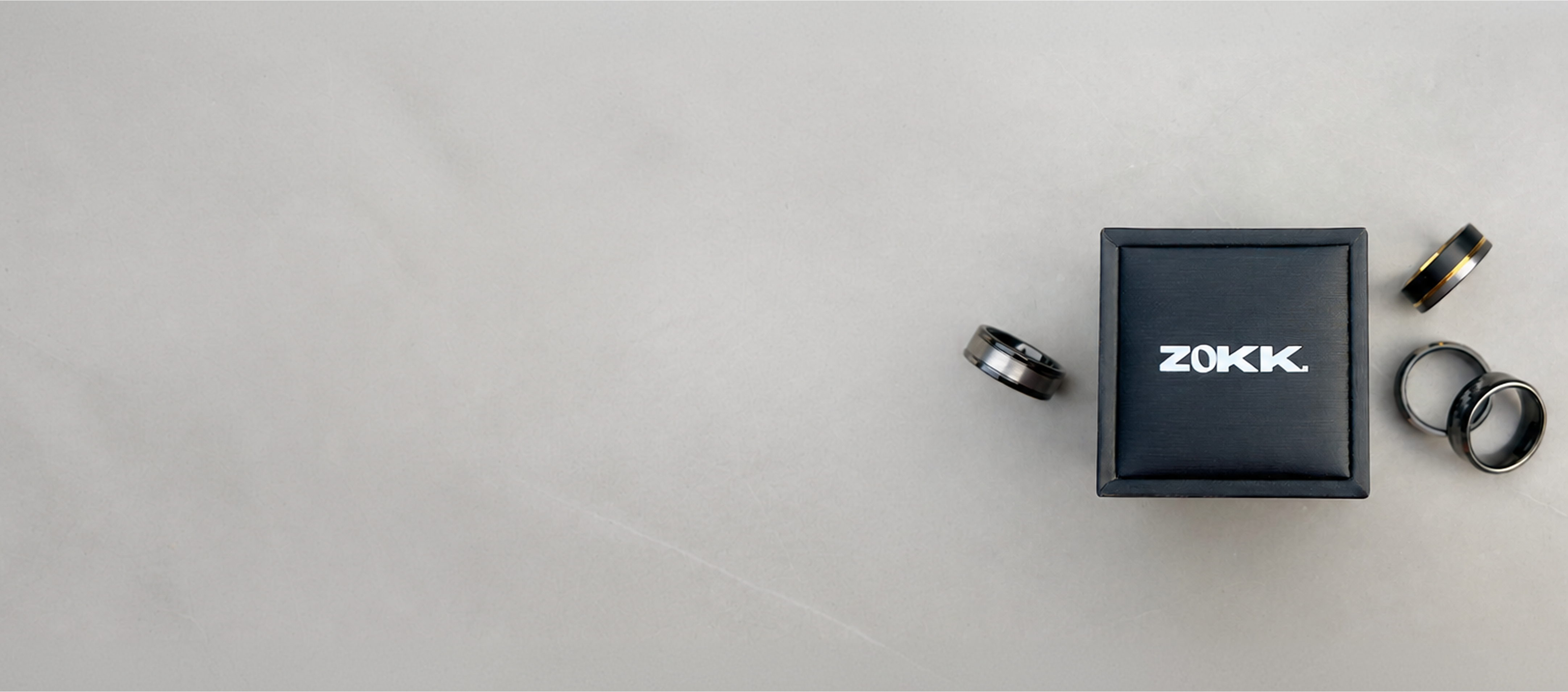 ZOKK ring box and rings on a light stone surface