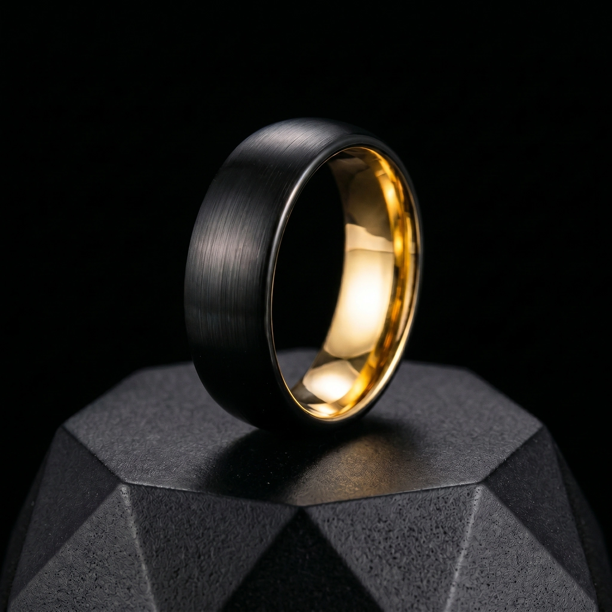 Black and gold ring on a faceted black pedestal