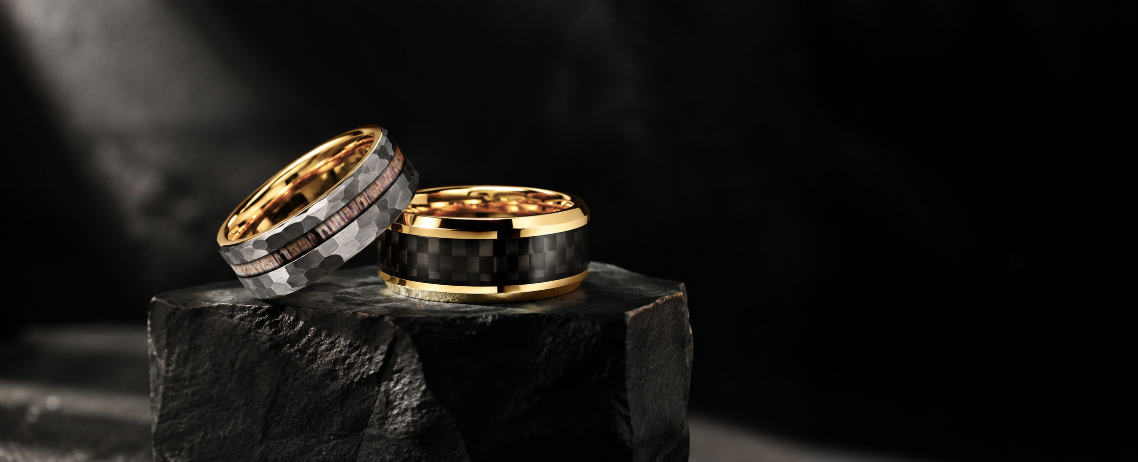 Two black and gold rings on a dark stone block
