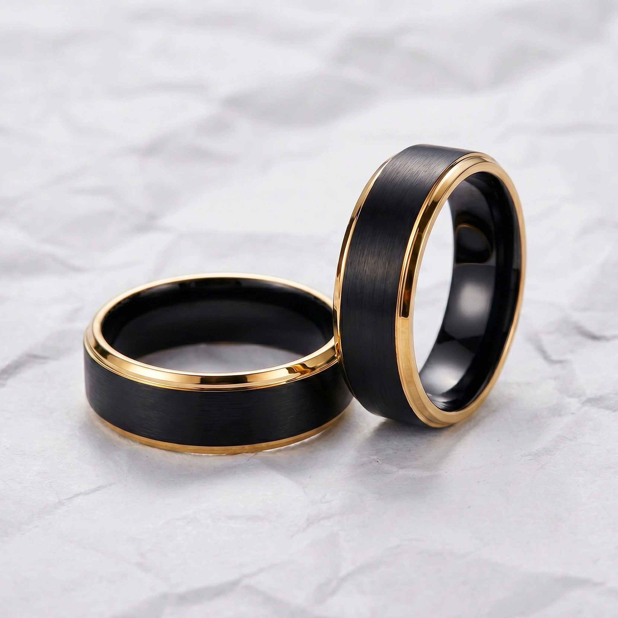 Two black and gold rings on white marble